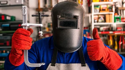 Soudeur tenant un serre-joint de soudure pour le maintien et le bridage de pièces métalliques