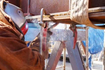 Un soudeur utilise des serre-joints pour maintenir une pièce avant soudage