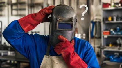 Soudeur en atelier portant un casque de soudage et des gants de protection, illustrant les questions liées aux techniques de soudure.
